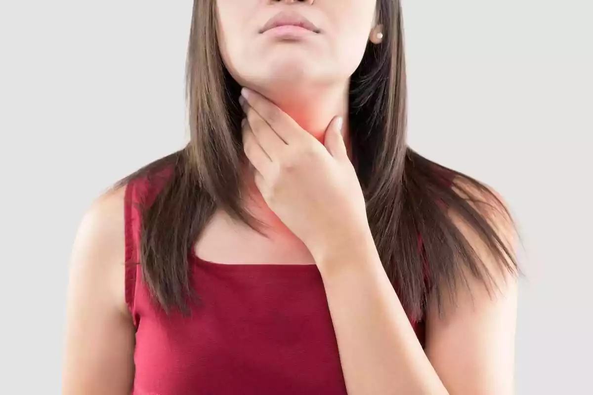 Mujer tocándose la región de la garganta por dolor