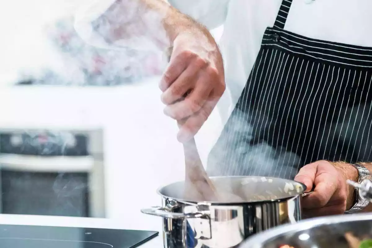 Hombre cocinando usando una olla y una cuchara de madera