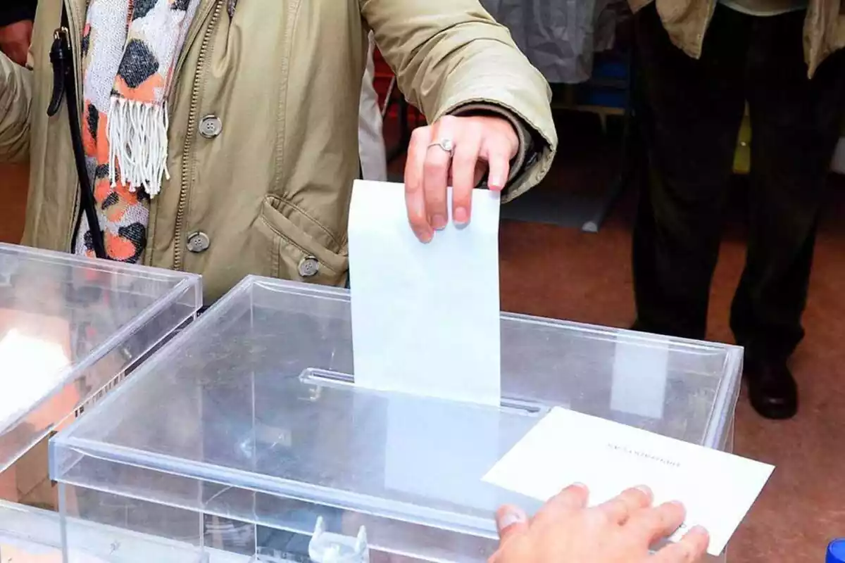 Persona introduciendo su voto en una urna electoral