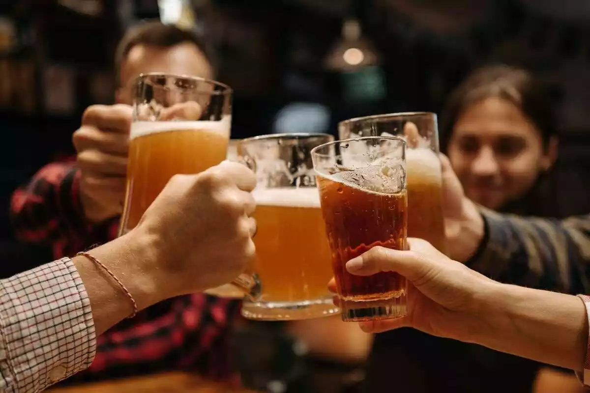 Grupo de personas brindando con jarras de cerveza en un bar