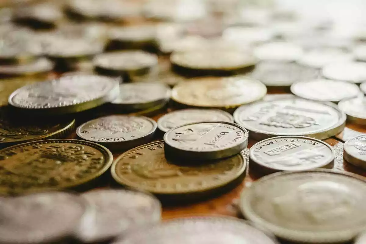 Muchas monedas de peseta encima de una mesa