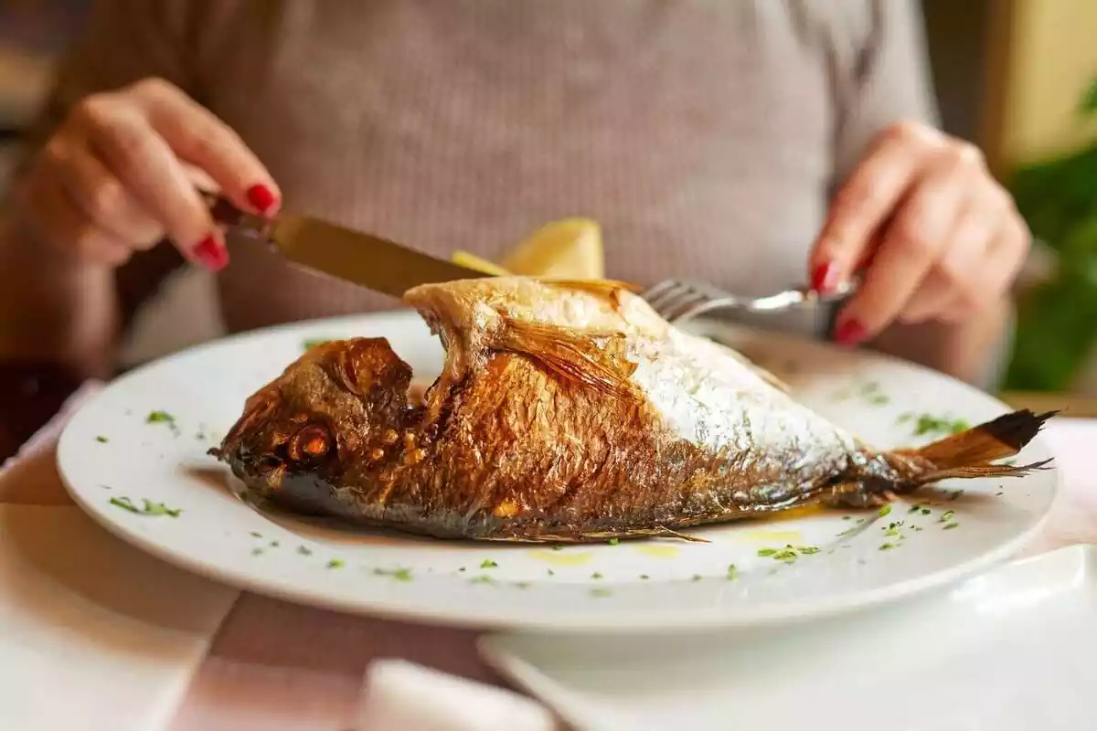 Plano de una persona cortando pescado en un restaurante