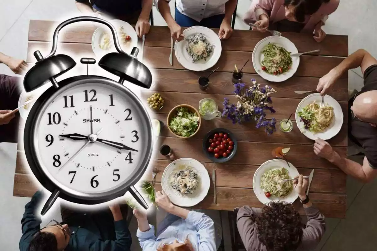 Montaje con un reloj en primer plano y de fondo una imagen de muchas personas comiendo en una mesa Montaje con un reloj en primer plano y de fondo una imagen de muchas personas comiendo en una mesa