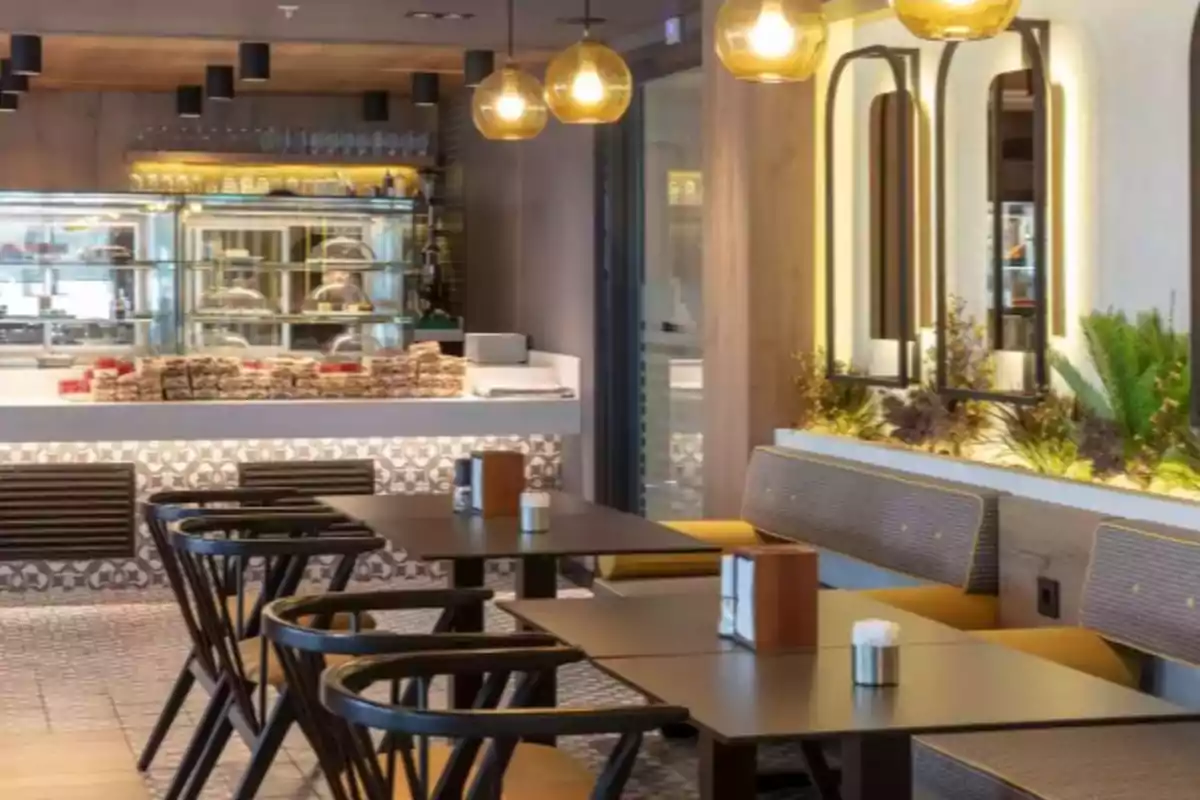 Un acogedor café moderno con mesas de madera, sillas elegantes, iluminación cálida y una barra con repostería en exhibición. Un acogedor café moderno con mesas de madera, sillas elegantes, iluminación cálida y una barra con repostería en exhibición.