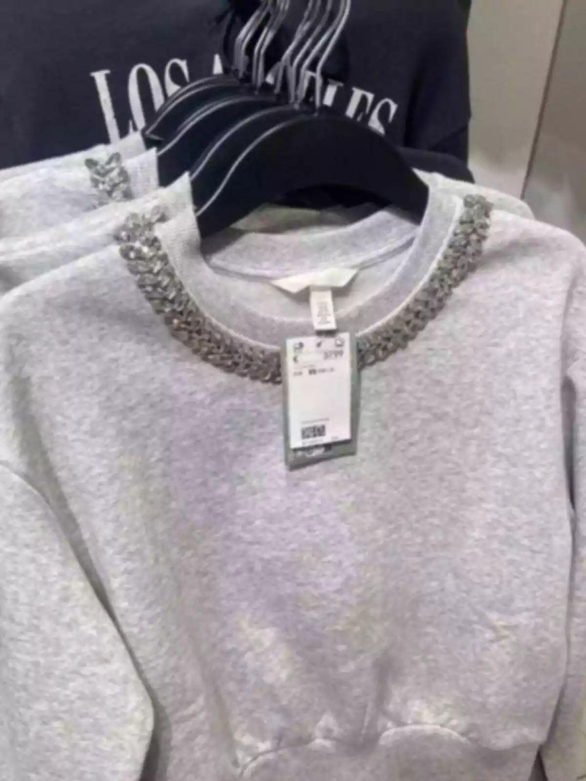 Sudadera gris con strass de H&M colgada en su percha en la tienda