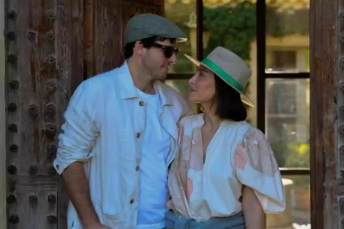 Una pareja -formada por Íñigo Onieva y Tamara Falcó- mirándose con cariño mientras posan juntos al aire libre frente a una puerta de madera. Una pareja -formada por Íñigo Onieva y Tamara Falcó- mirándose con cariño mientras posan juntos al aire libre frente a una puerta de madera.