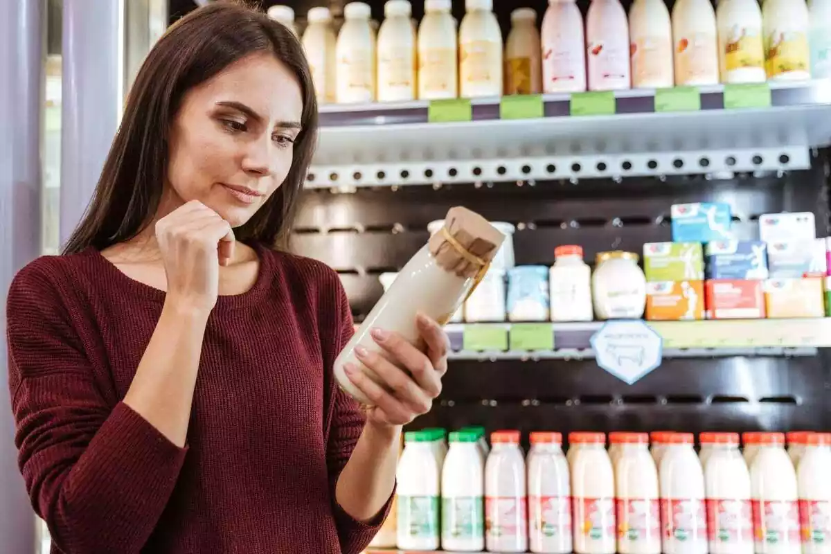 Primer plano de una mujer comprando yogur líquido en un supermercado
