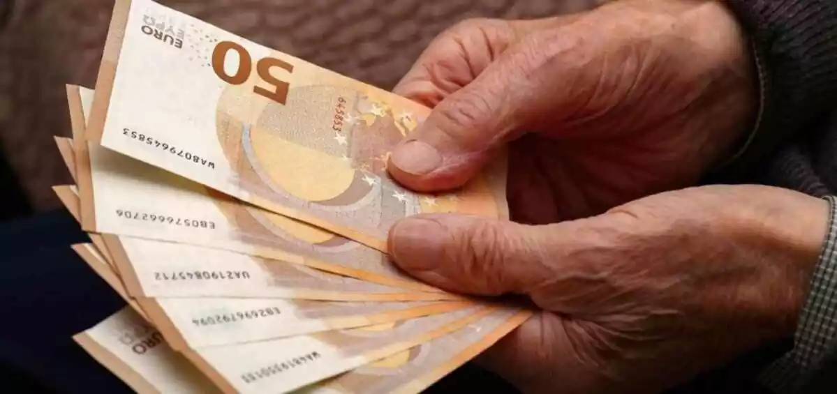 Una persona mayor sosteniendo en sus manos billetes de 50 euros
