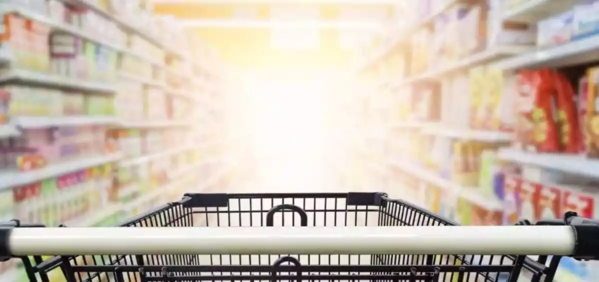 Un carrito de supermercado en un pasillo lleno de productos