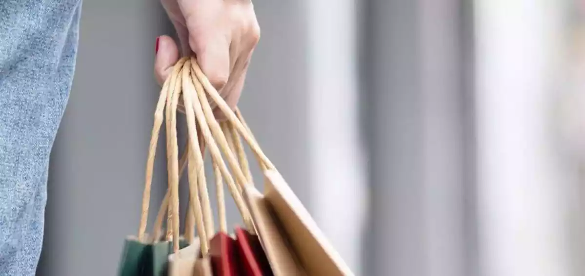 Una mujer sujetando varias bolsas llenas de compras con la mano